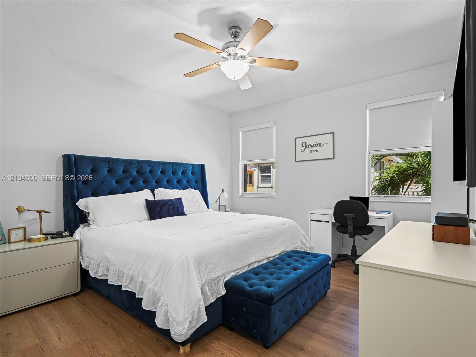 Wood-finish flooring, dual windows with roller shades, and a ceiling fan with integrated light fixture Wood-finish flooring, dual windows with roller shades, and a ceiling fan with integrated light fixture