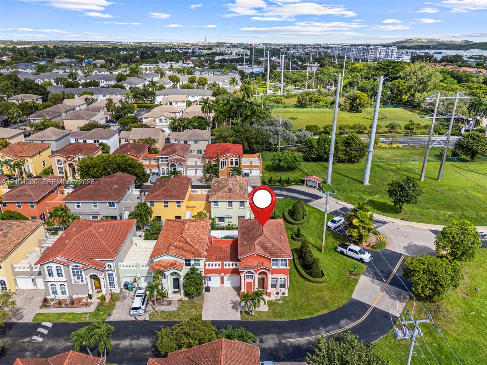 Two-story stucco exterior featuring a multi-pitched tile roof, arched entryway, and integrated multi-car garage, set on a corner lot with landscaped greenery