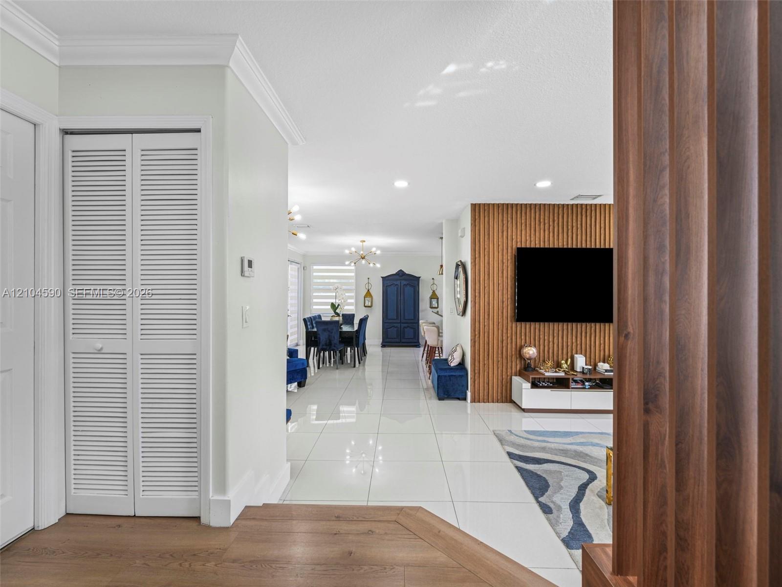Wood-finish flooring, white polished tile flooring, vertical slat wood accent wall, and white louvered-style closet doors