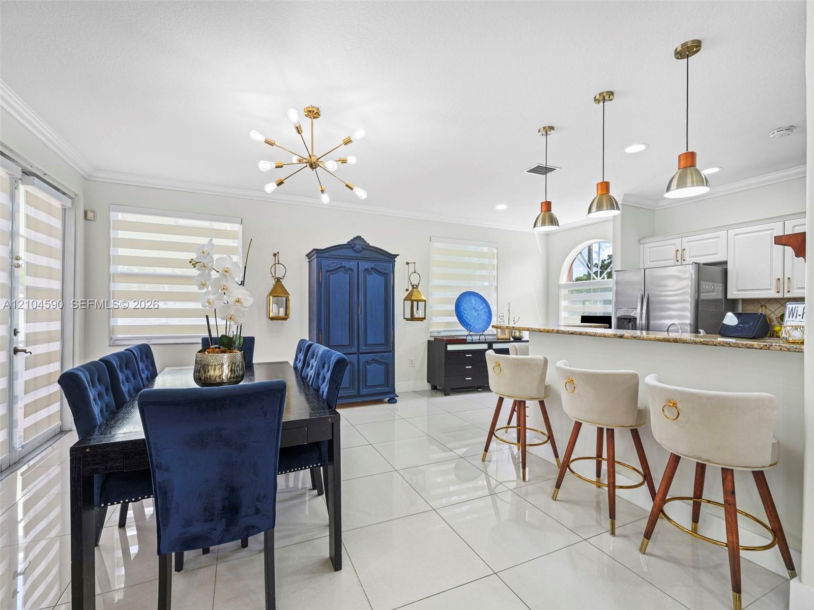 Open-concept space featuring polished tile flooring, kitchen with stone countertops, breakfast bar, multi-arm sputnik chandelier, and recessed lighting