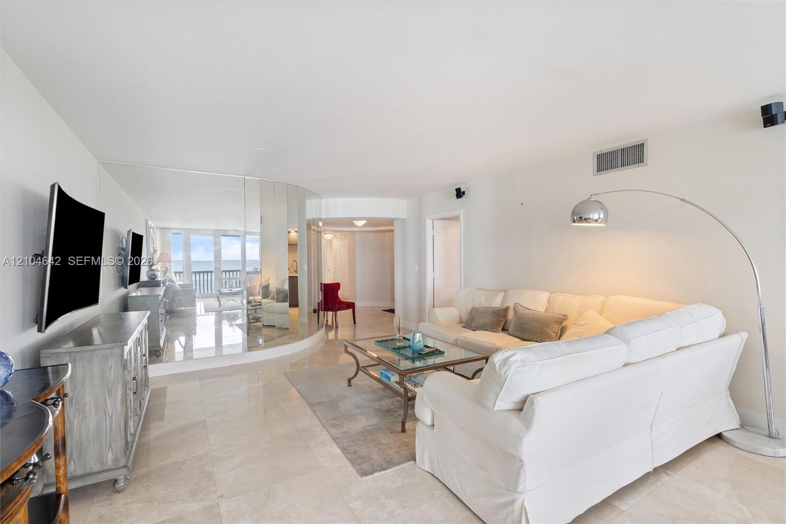 Living area featuring stone-finish flooring, a floor-to-ceiling mirrored wall, and floor-to-ceiling glass doors with access to an exterior balcony