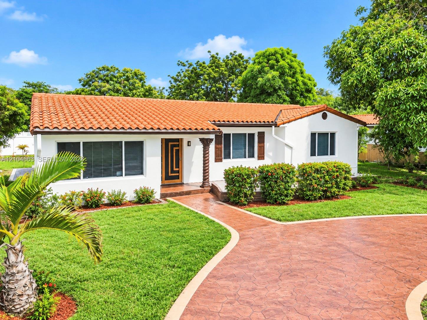 Single-story exterior featuring a terracotta tile roof, white stucco facade, decorative spiral support column, and a stamped concrete driveway