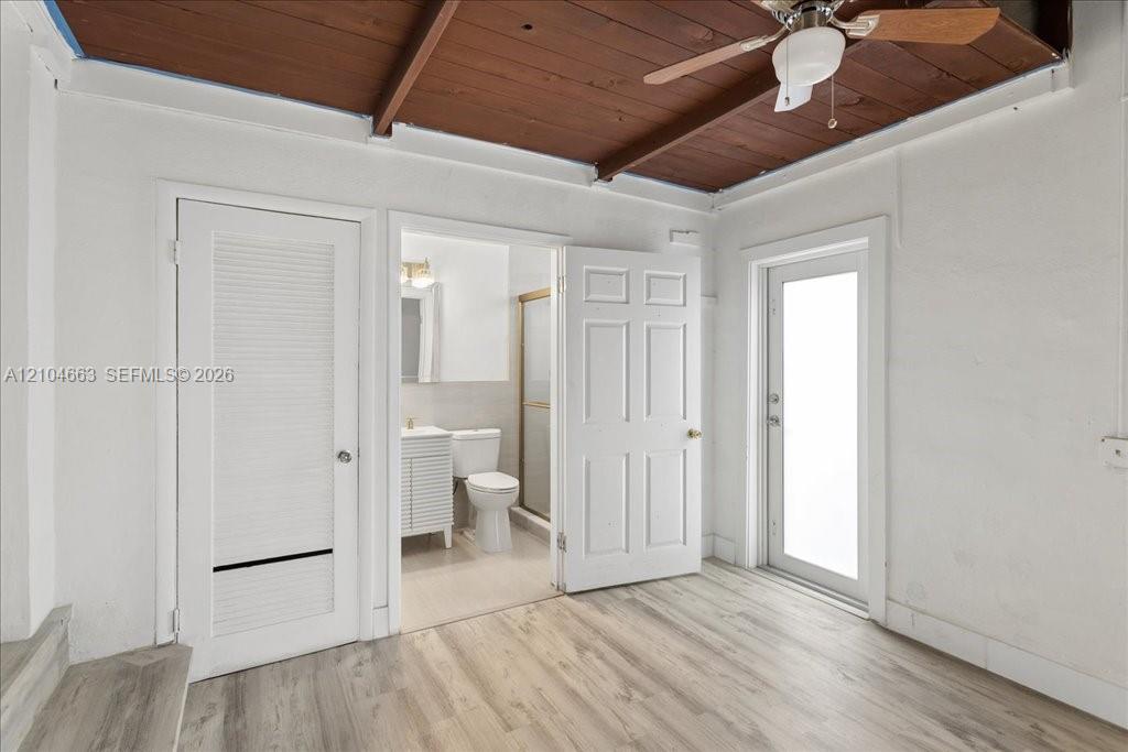 Exposed wood-plank ceiling with ceiling fan, light-toned wood-finish flooring, and white paneled doors Exposed wood-plank ceiling with ceiling fan, light-toned wood-finish flooring, and white paneled doors