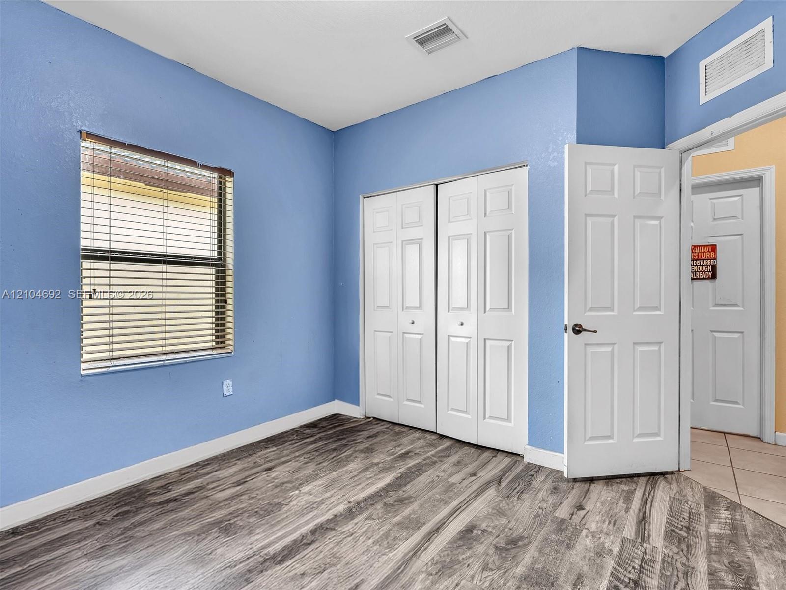 Room featuring wood-finish flooring, two-panel interior doors, and a double-door closet