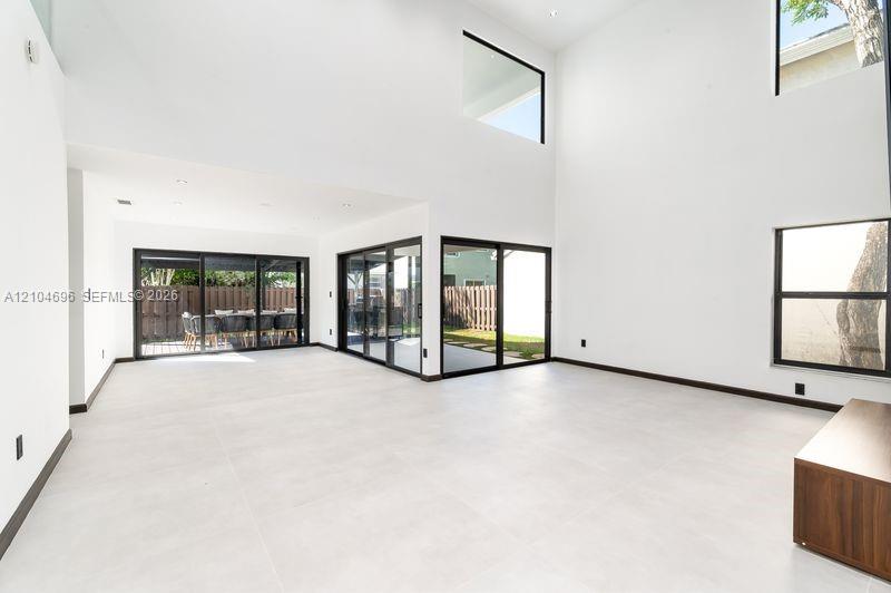 Double-height ceilings, large-format tile flooring, recessed lighting, and expansive glass sliding doors with black frames Double-height ceilings, large-format tile flooring, recessed lighting, and expansive glass sliding doors with black frames