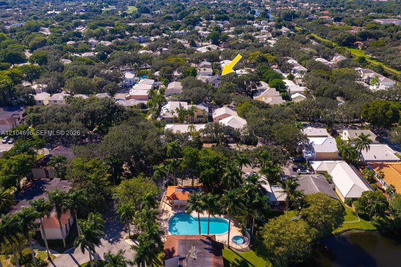 Aerial perspective highlighting a mature residential neighborhood featuring abundant tree canopy and a community recreation area with a swimming pool and spa