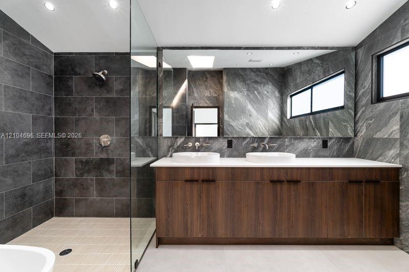 Double vanity featuring a wood-finish cabinet, white solid-surface countertop, dual vessel sinks, and wall-mounted faucets