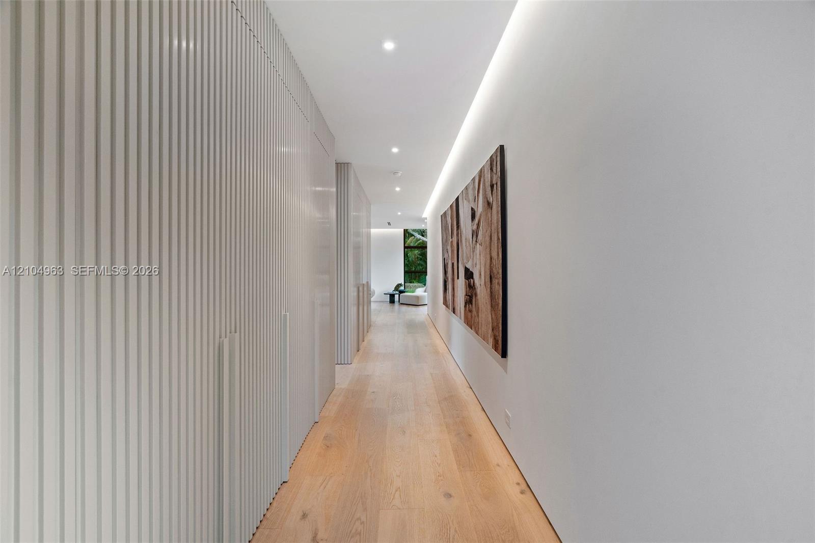 Hallway featuring floor-to-ceiling slatted built-in cabinetry, wood-finish flooring, and recessed architectural cove lighting