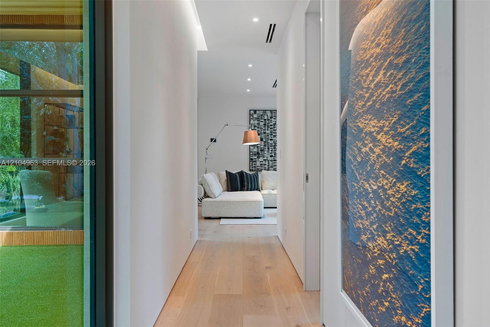 Hallway featuring wood-finish flooring, recessed lighting, and expansive floor-to-ceiling glass wall panels