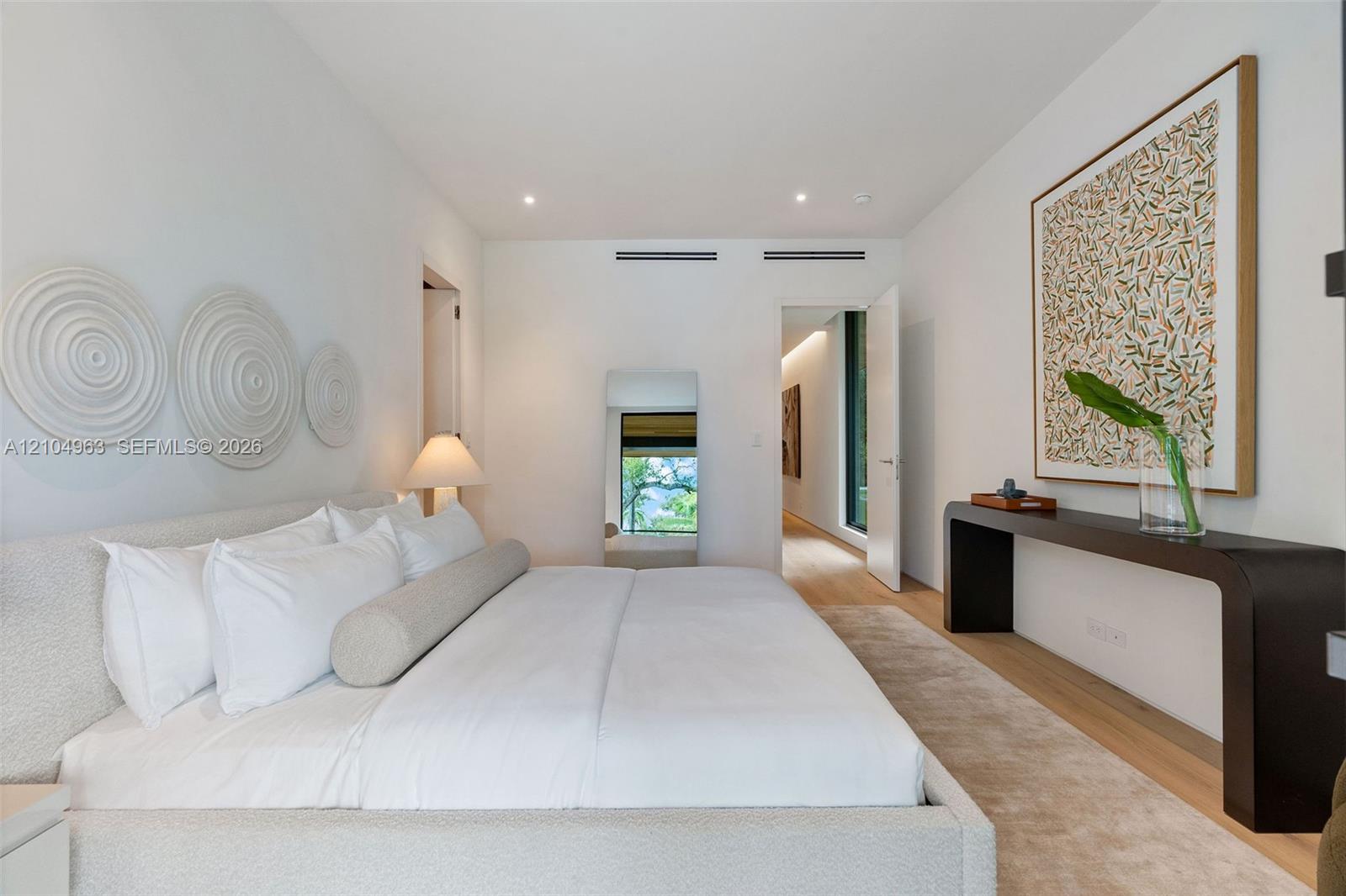 Spacious room featuring light-toned wood-finish flooring, recessed ceiling lighting, and smooth white walls