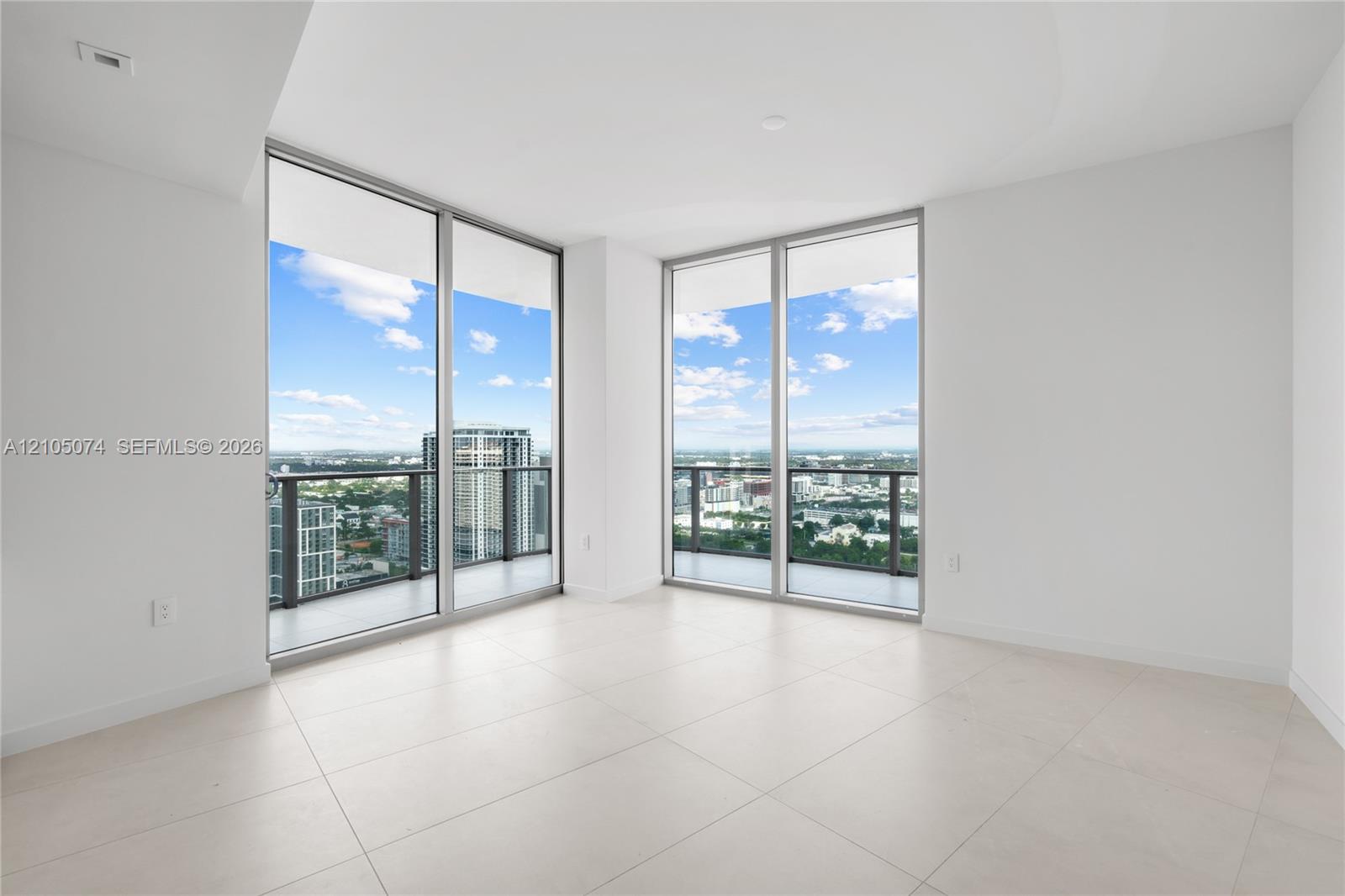 Floor-to-ceiling glass walls, wrap-around balcony access, large-format tile flooring, and neutral interior finishes