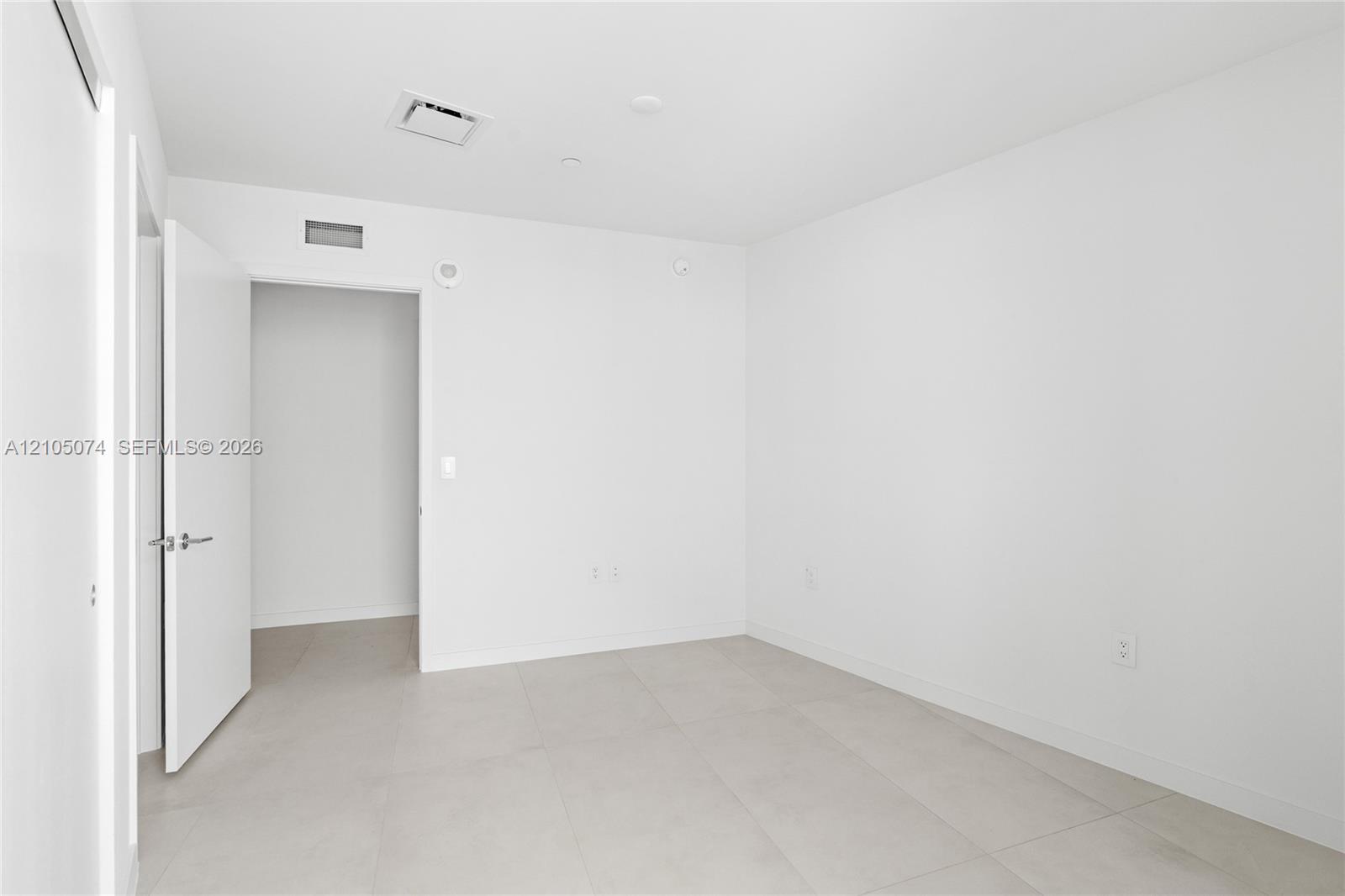 Neutral-toned interior space featuring light-colored tile flooring and minimalist, crisp white walls