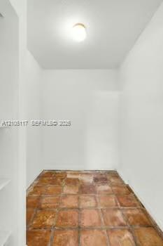 Enclosed space featuring square terra-cotta tile flooring, recessed wall shelving, and a dome-style ceiling light fixture
