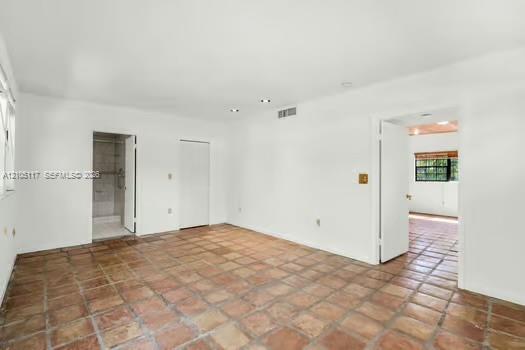 Interior room featuring terracotta tile flooring, recessed ceiling lighting, and multi-panel solid-core interior doors