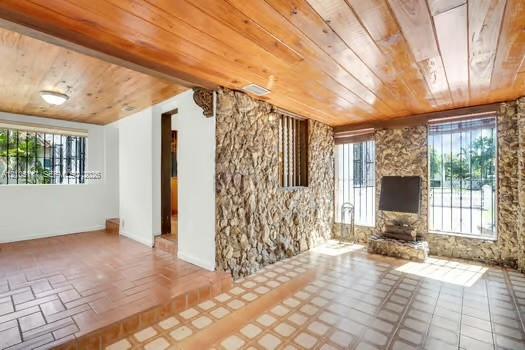 Natural stone accent wall, wood-plank ceiling, and tiled flooring featuring a split-level design