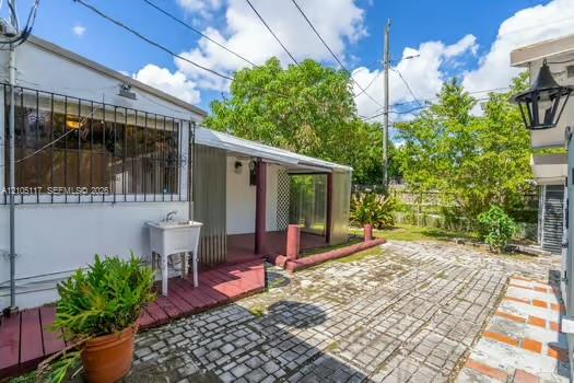 Exterior area featuring a paved stone patio, a covered wooden deck, and a utility sink