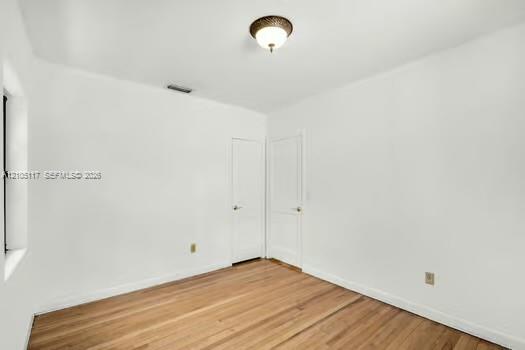 Room featuring wood-finish flooring, white walls, and a flush-mount ceiling light fixture