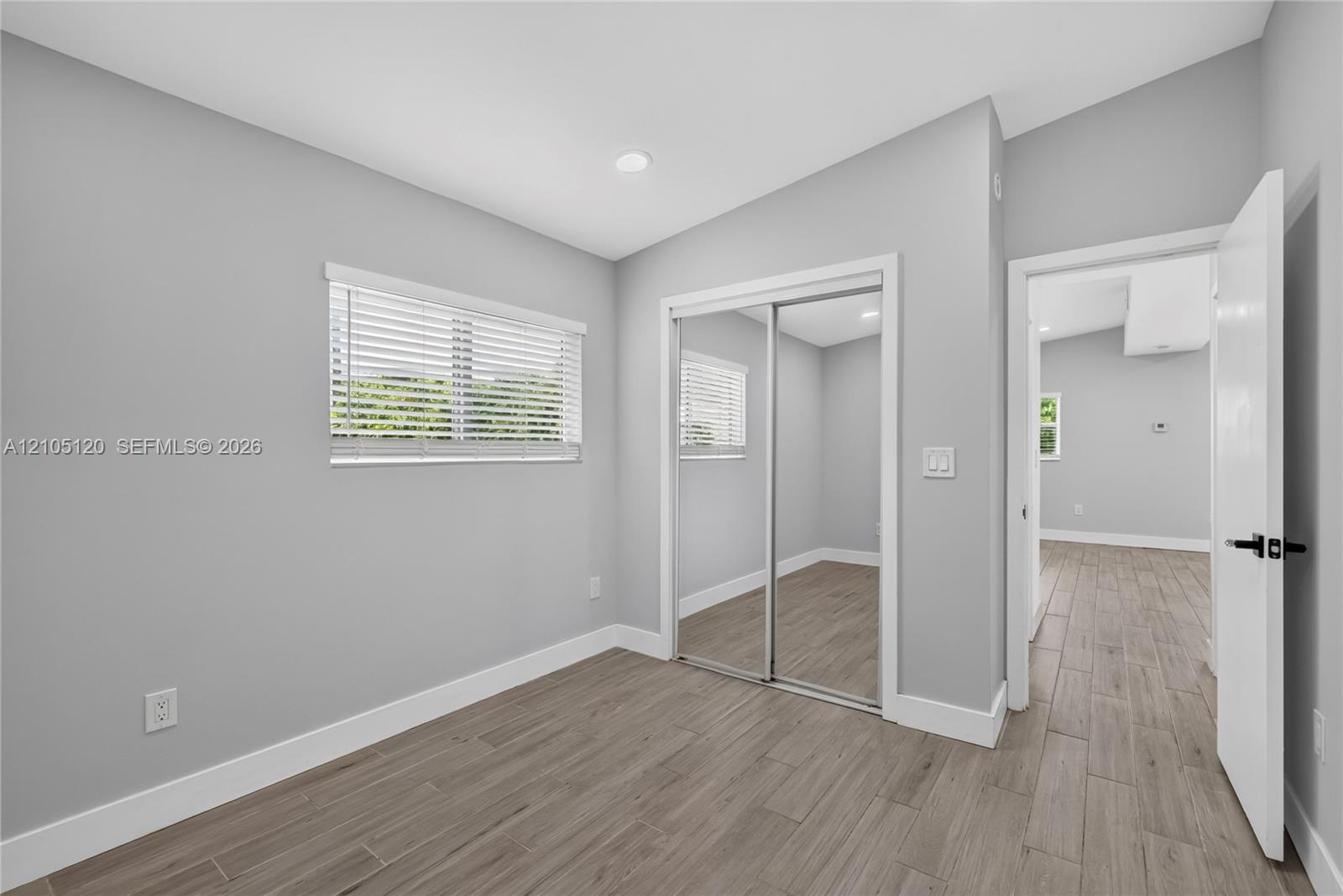 Wood-finish plank flooring, neutral wall tones, recessed lighting, and a closet with sliding mirrored doors