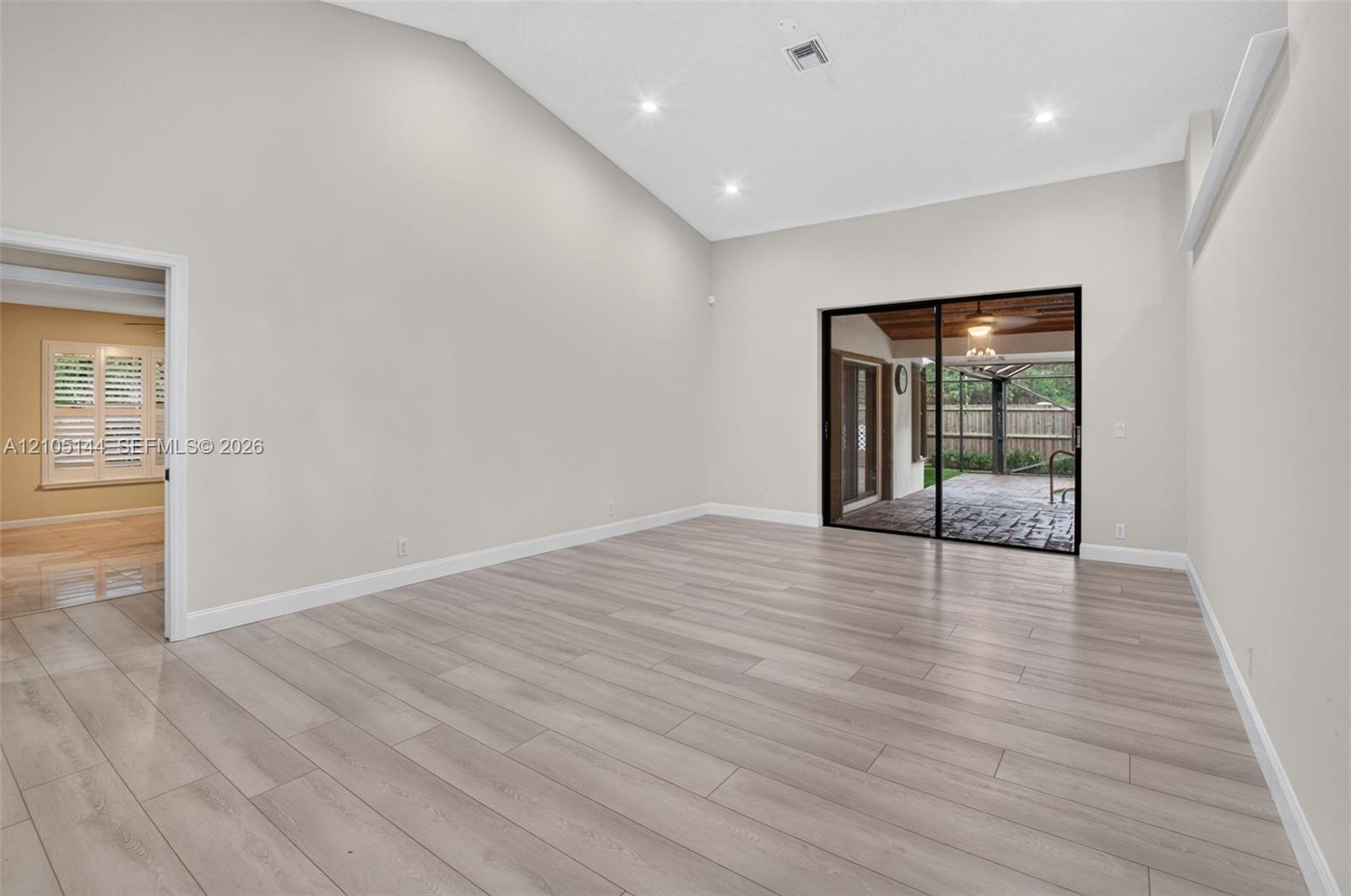 Vaulted ceiling featuring recessed lighting, wood-finish flooring, and sliding glass doors