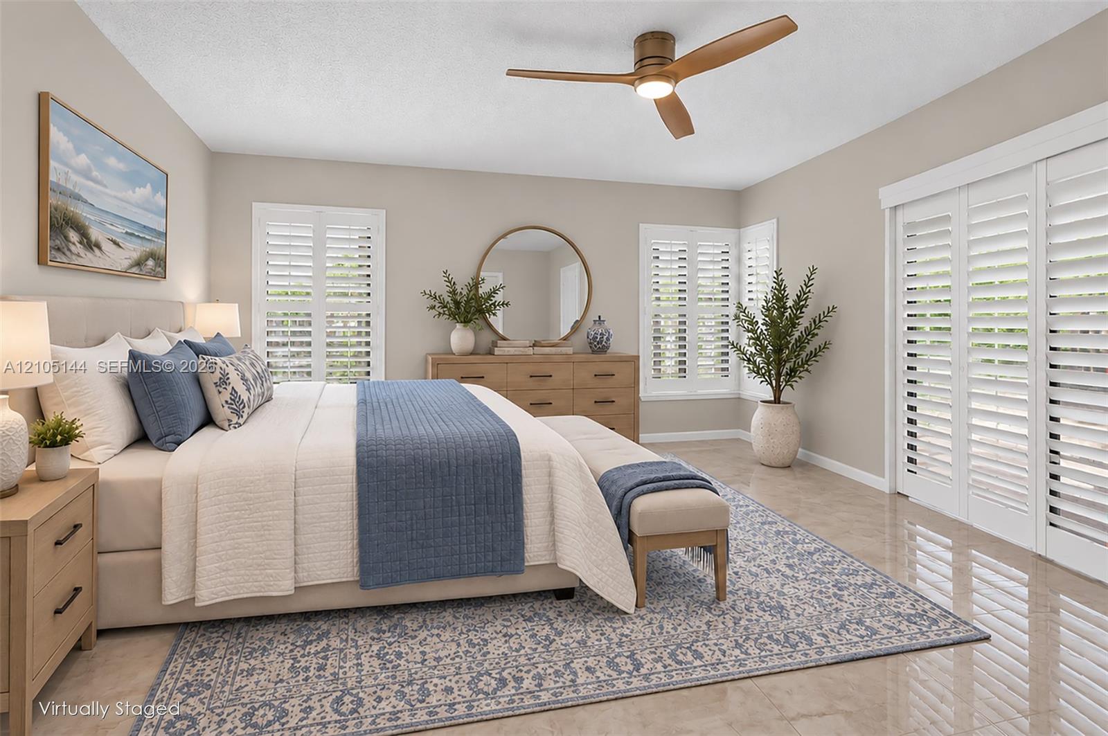 Neutral-toned bedroom featuring large-format tile flooring, plantation shutters, and a modern three-blade ceiling fan with integrated lighting
