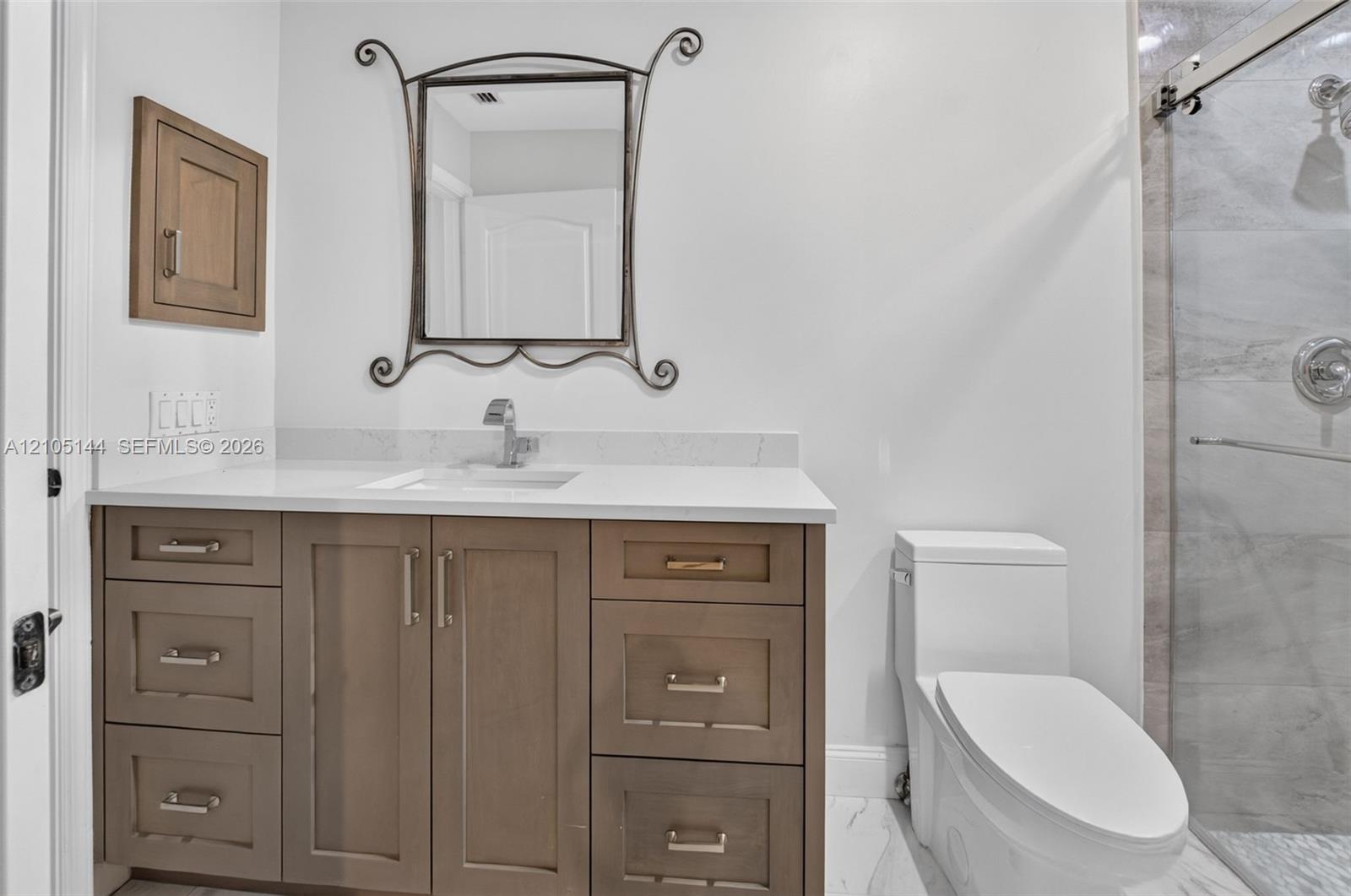 Bathroom vanity featuring light-toned cabinetry, a stone-composite countertop with an integrated rectangular sink, and polished nickel hardware