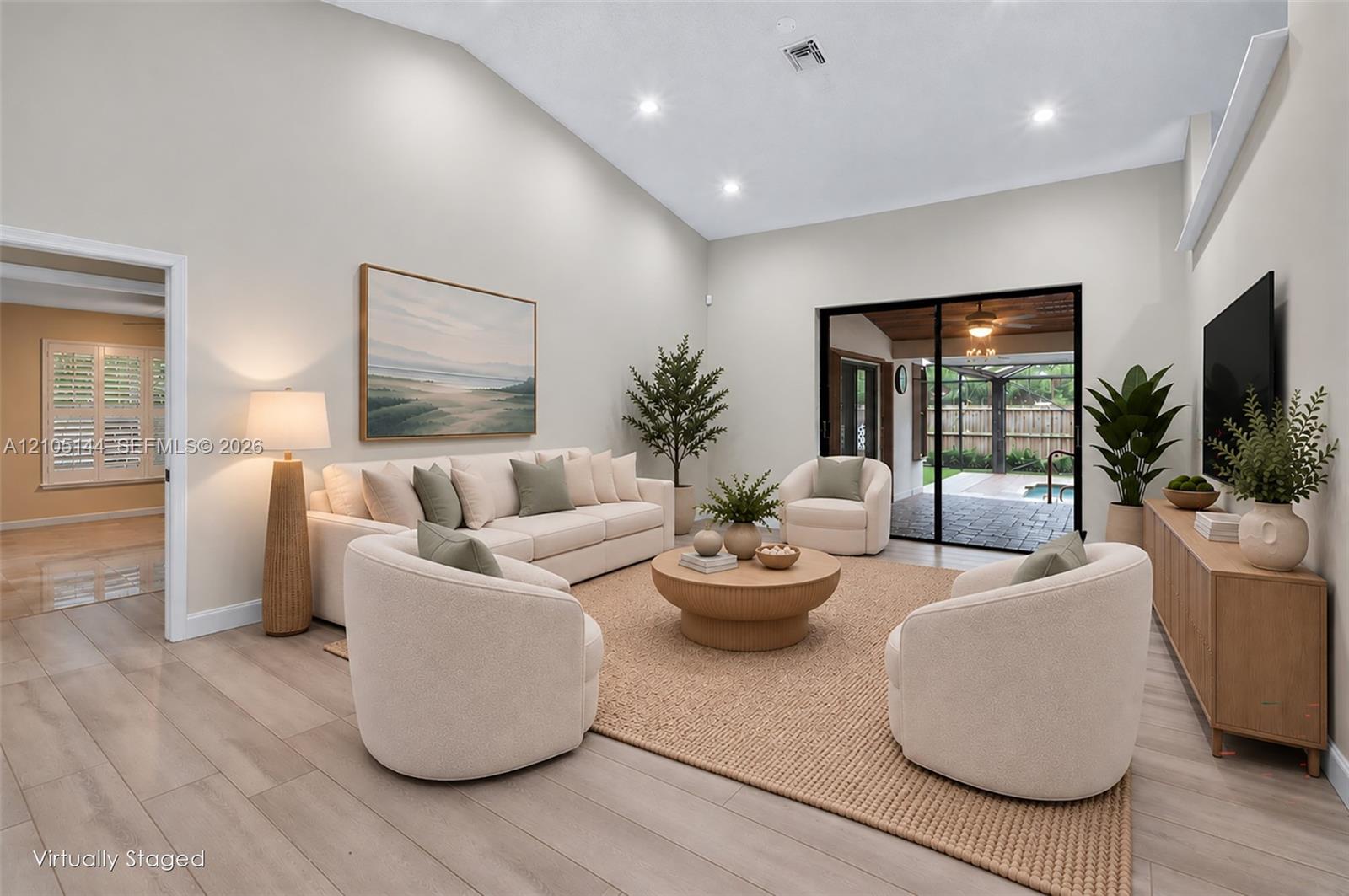 Living area featuring a vaulted ceiling, wood-finish flooring, recessed lighting, and large sliding glass doors leading to the exterior