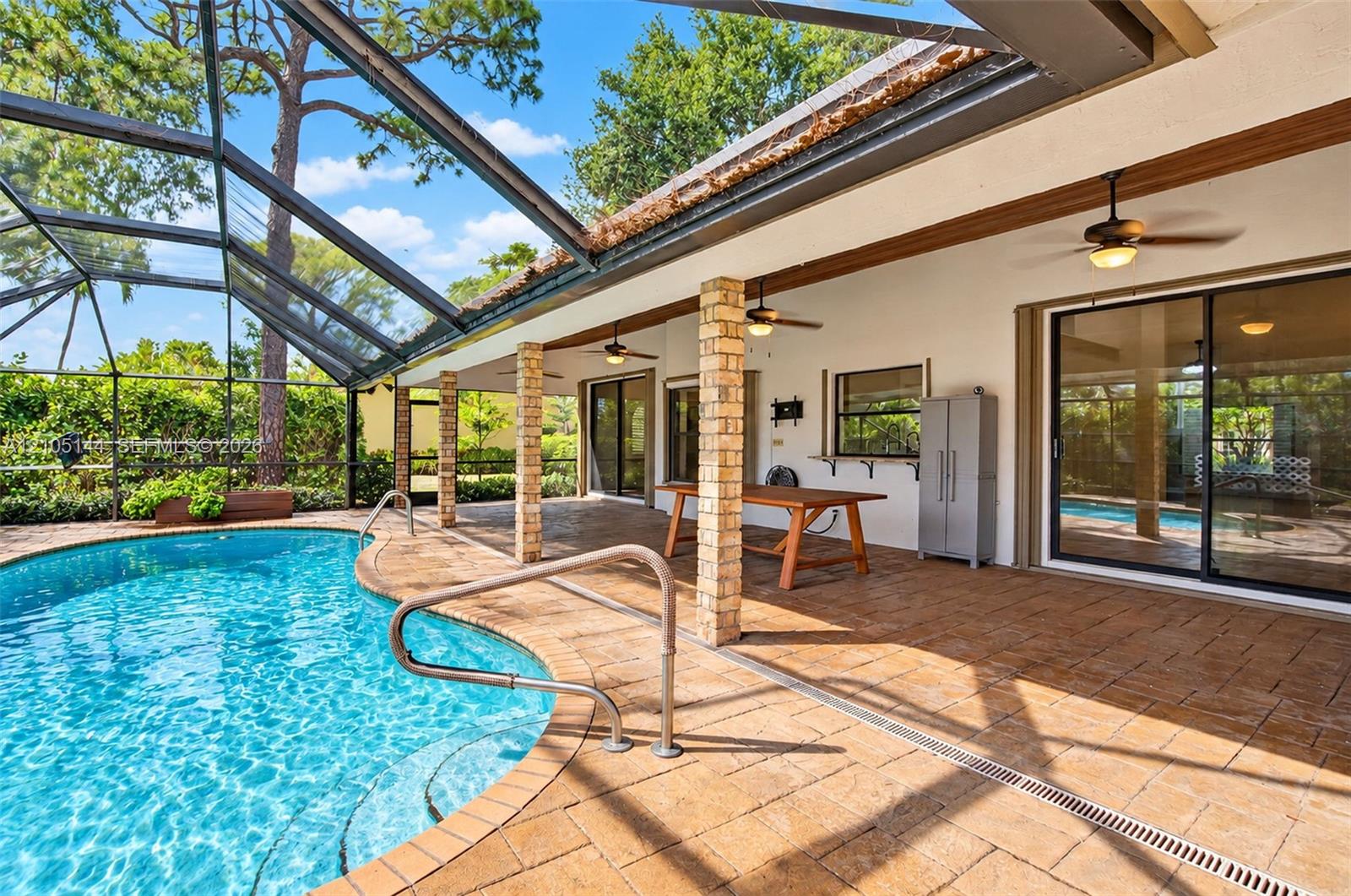 Screen-enclosed patio featuring a paver deck, brick support columns, recessed ceiling fans, and an inground pool with metal railings