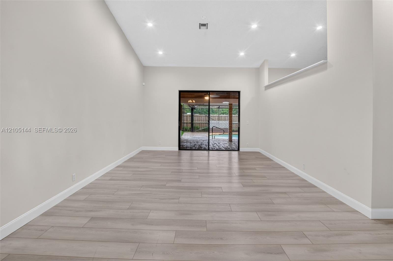 Open interior featuring high ceilings, recessed lighting, wood-finish flooring, and sliding glass doors