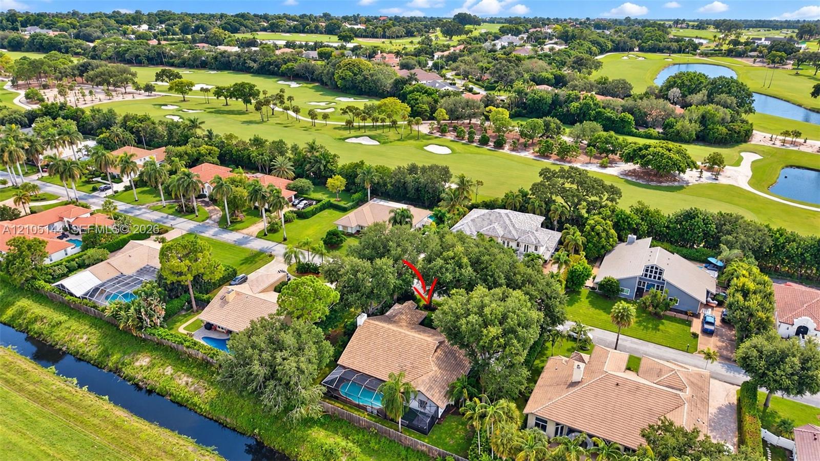 Aerial perspective of a residential neighborhood featuring golf course grounds, expansive fairway scenery, bodies of water, and mature landscaping