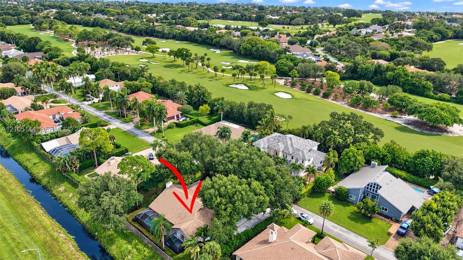 Aerial perspective featuring a multi-pitched shingle roof, screened-in lanai, and landscaped grounds situated on a waterway