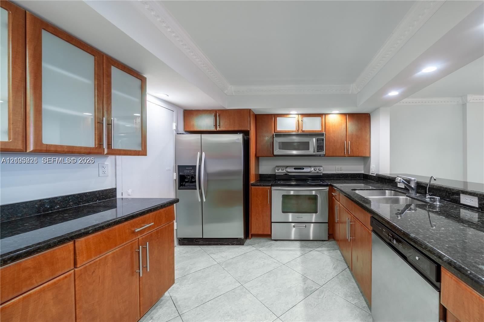 Kitchen featuring wood cabinetry, stone countertops, stainless steel appliances, and tile flooring