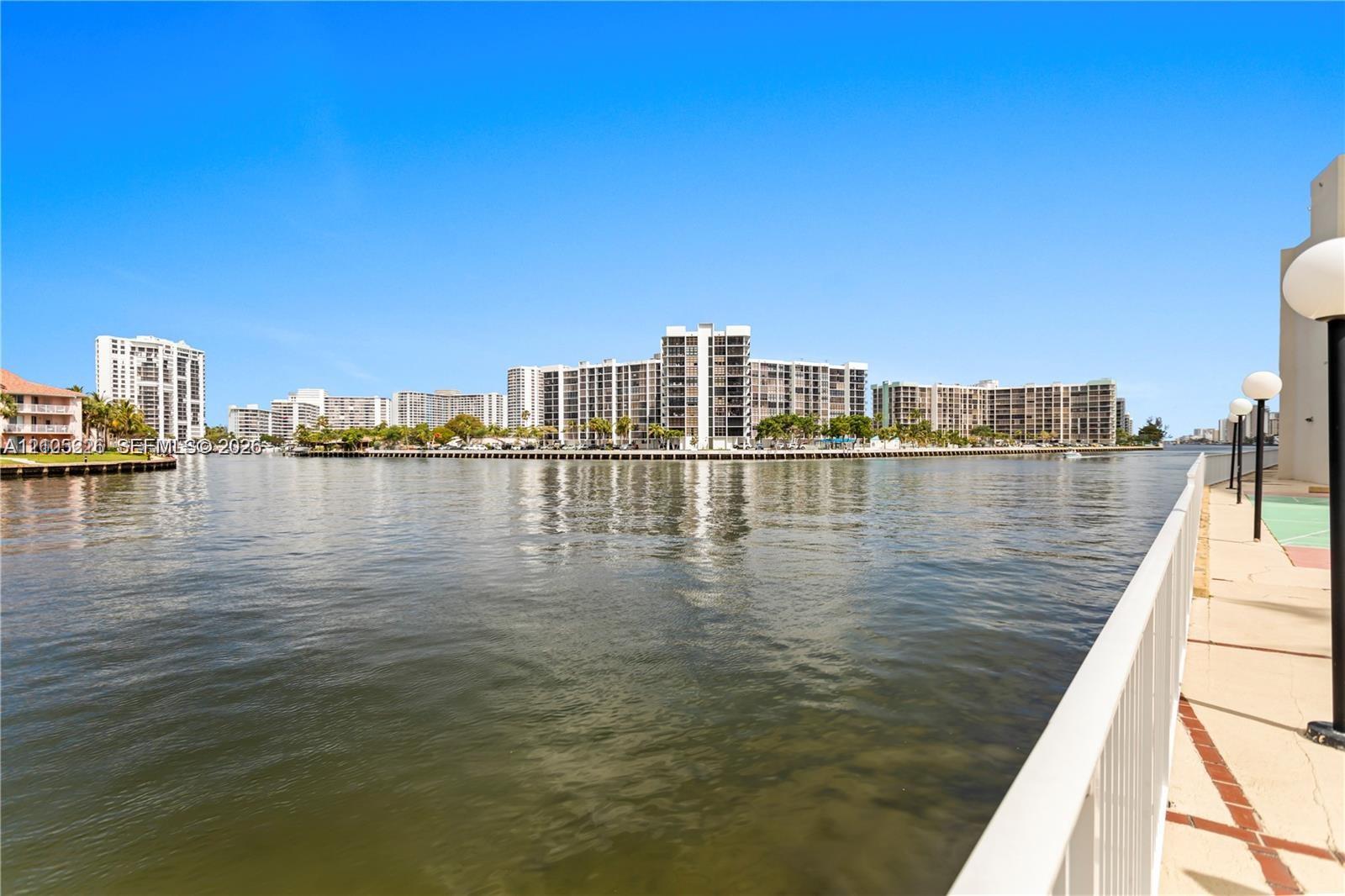 Waterfront patio featuring a paved surface, built-in outdoor grill, painted sports court, and metal railing enclosure