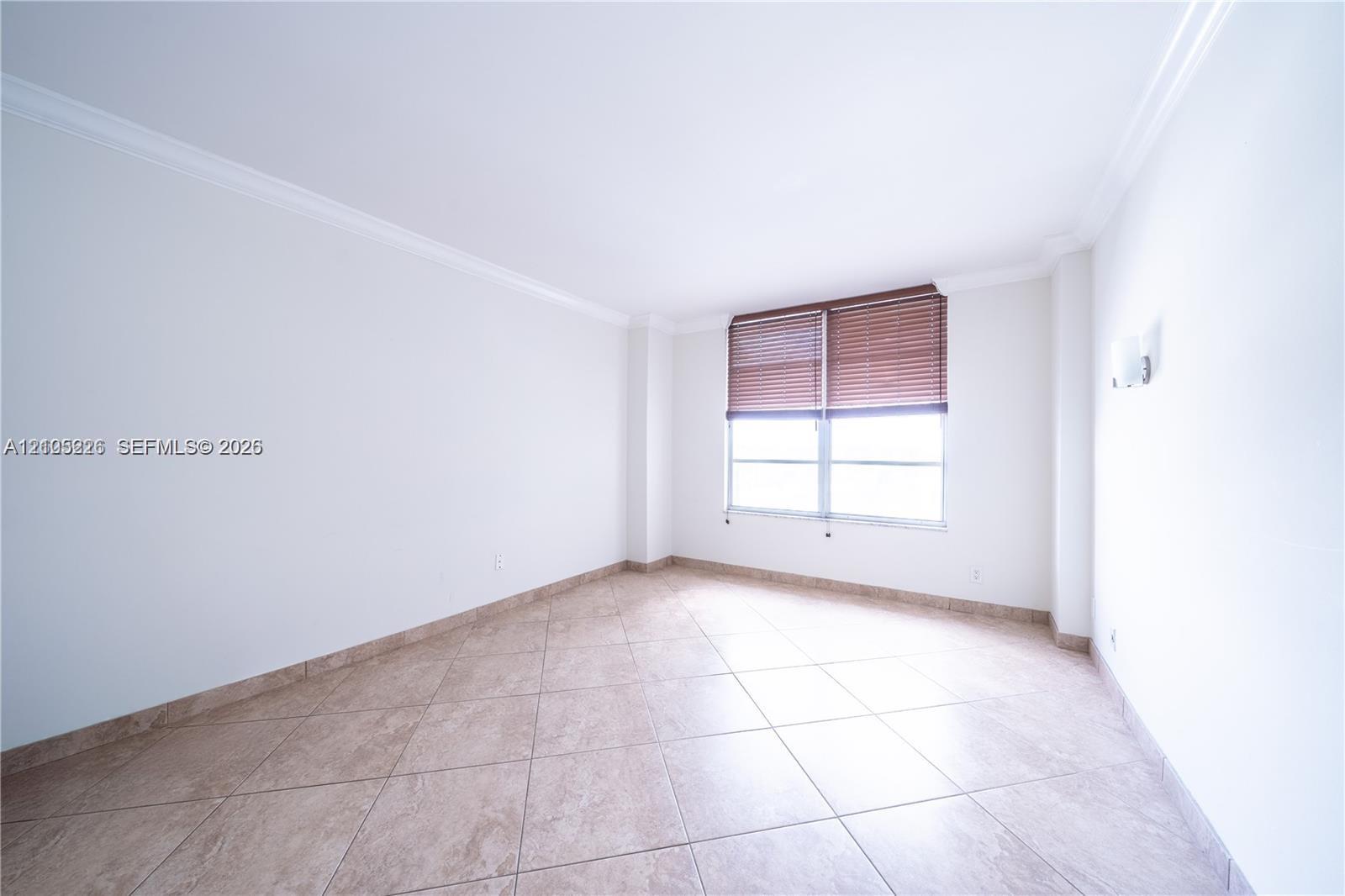 Open-concept interior featuring oversized tile flooring, crown molding, and expansive multi-pane windows with built-in wall-mounted light fixtures