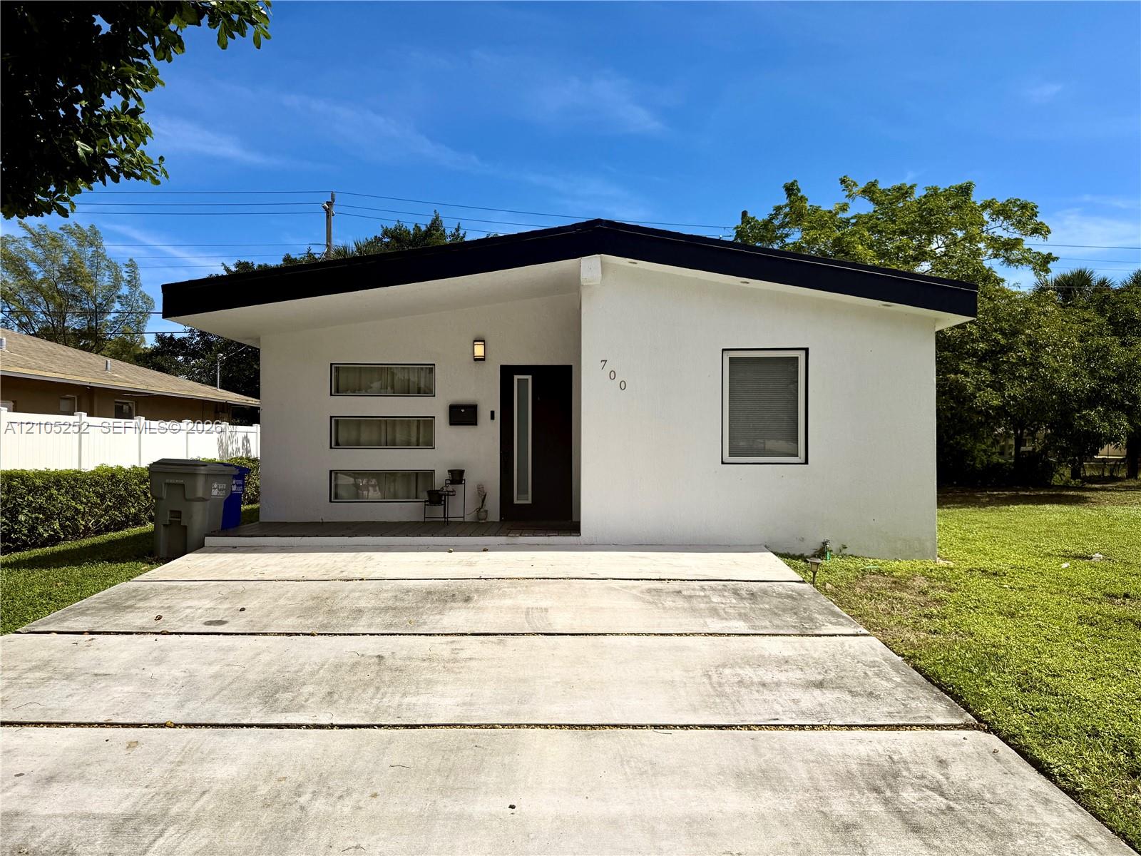 Contemporary architectural style with a flat black roofline, white stucco exterior, and a dark entry door