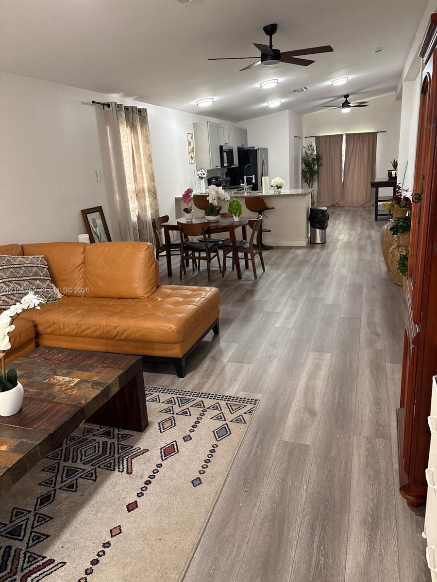 Open-concept living area featuring wood-finish flooring, recessed lighting, and ceiling fans