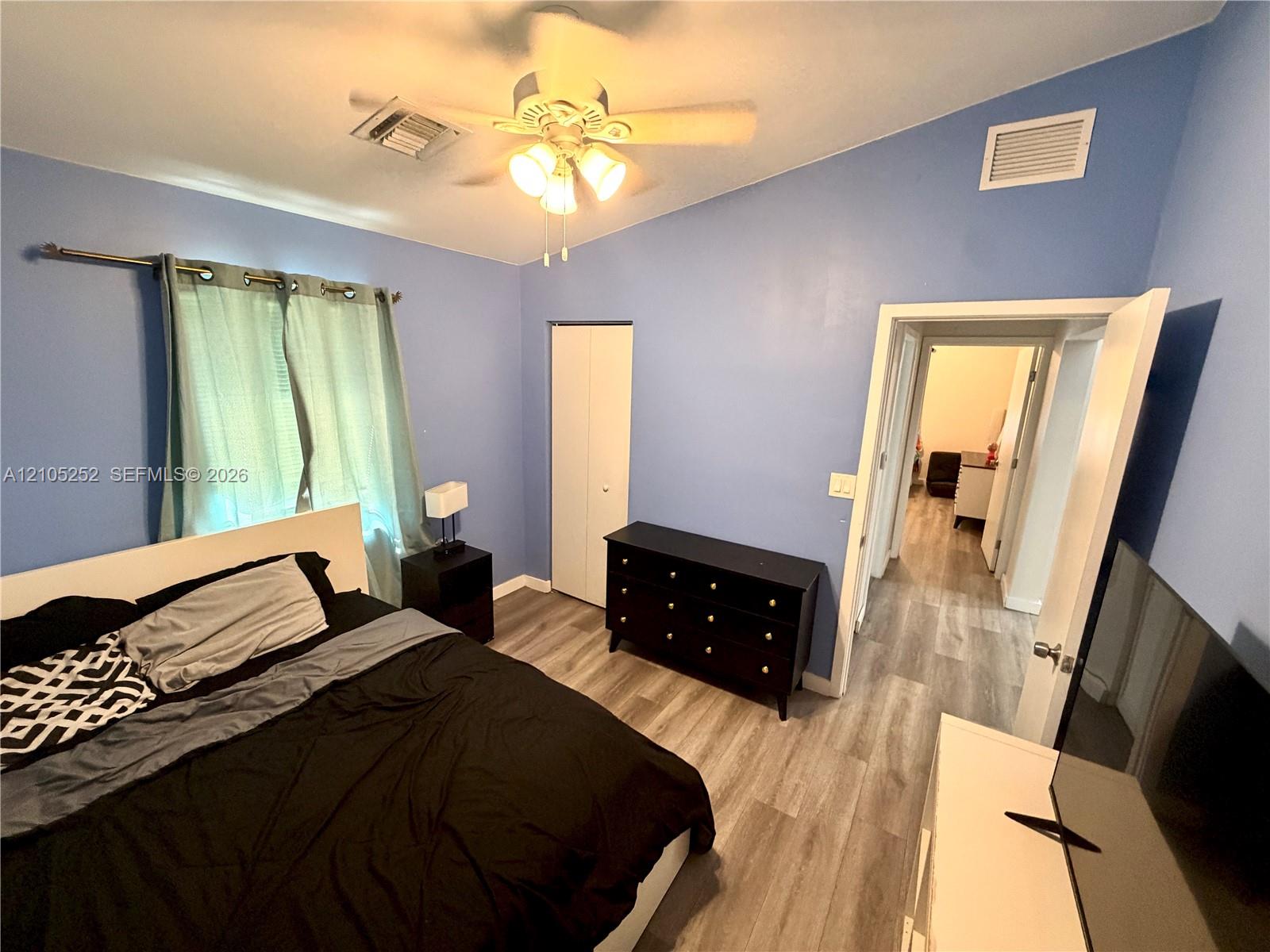 Vaulted ceilings with a ceiling fan, wood-finish flooring, and bi-fold closet doors