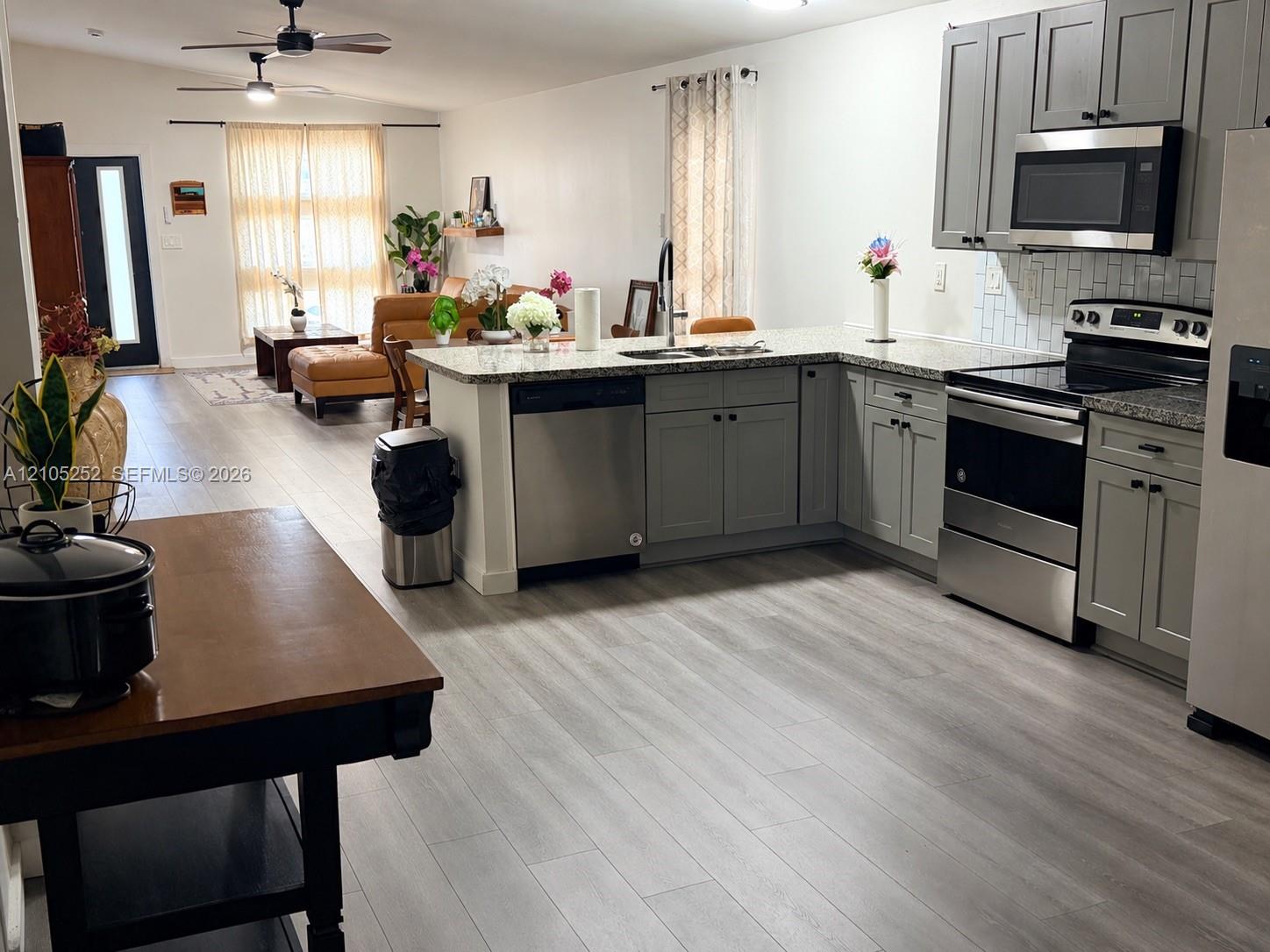 Kitchen featuring gray cabinetry, stainless steel appliances, and a light-colored backsplash