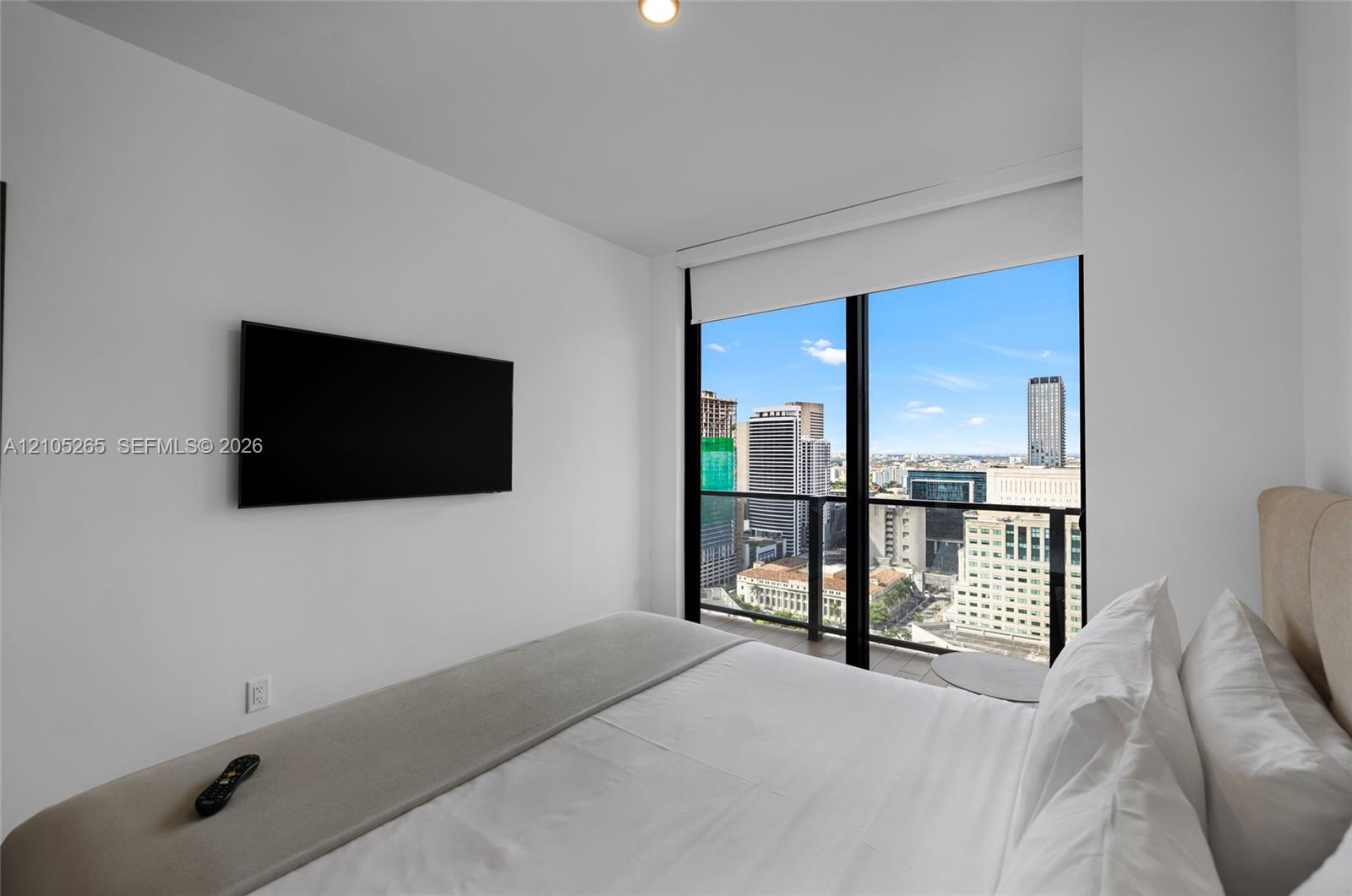 Floor-to-ceiling windows featuring urban skyline scenery and an attached glass-railing balcony
