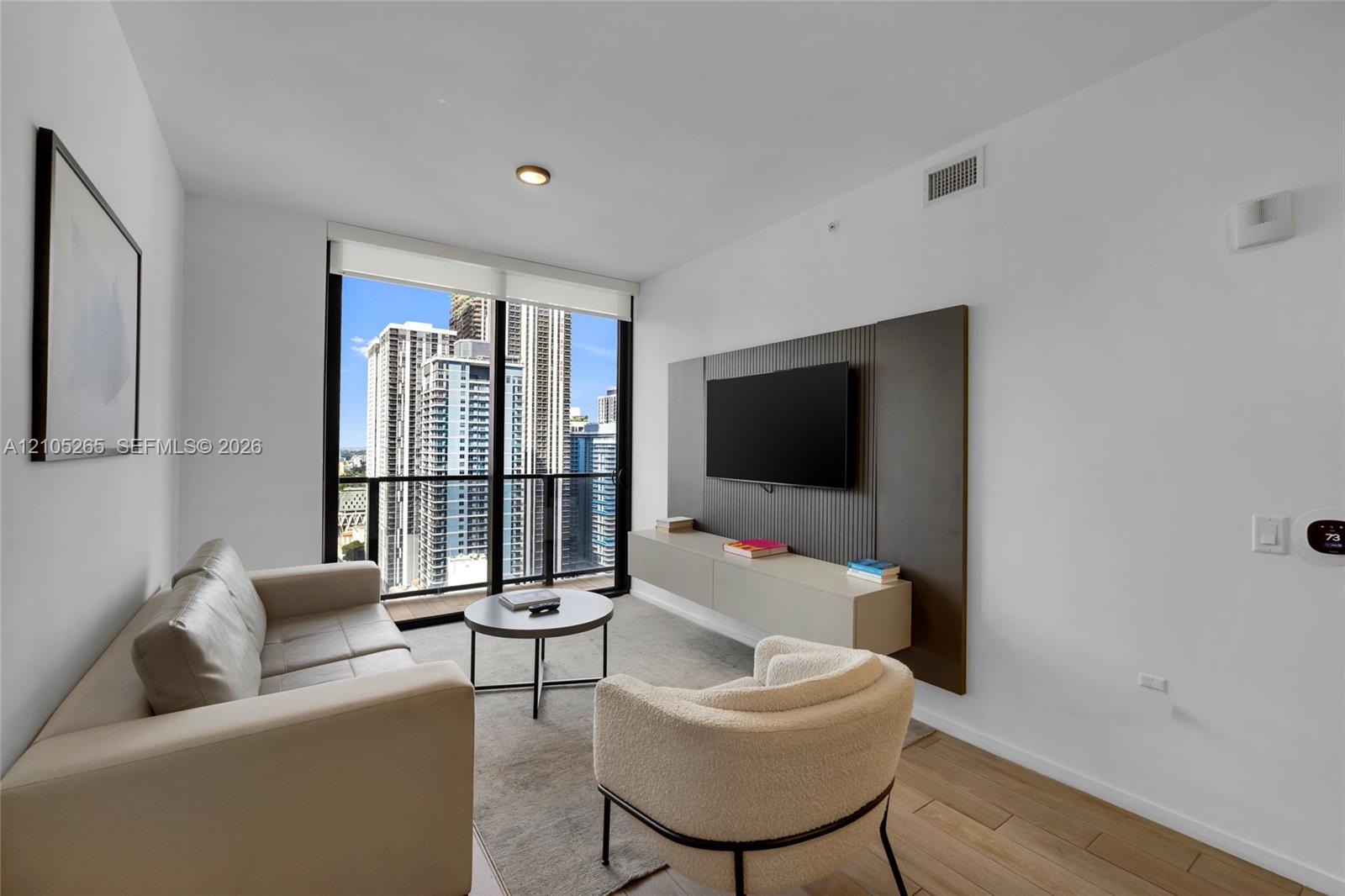 Floor-to-ceiling windows, wood-finish flooring, custom wall paneling, and a wall-mounted floating cabinet