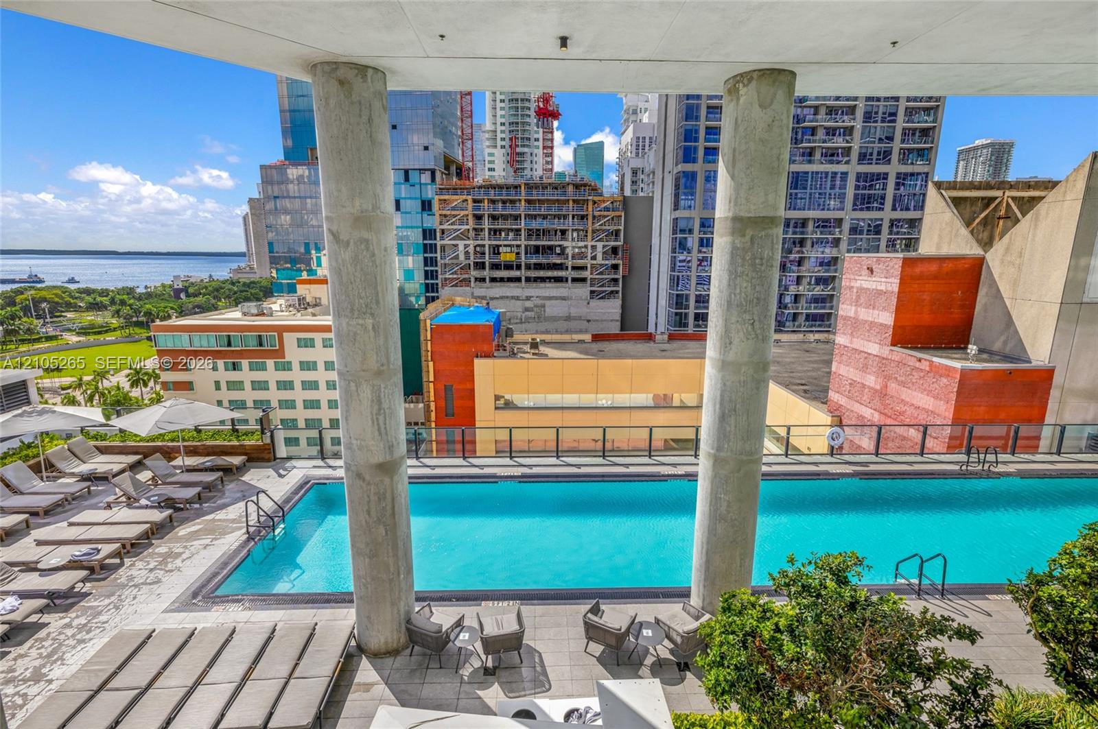Outdoor swimming pool featuring a concrete terrace, structural support columns, and metal railings