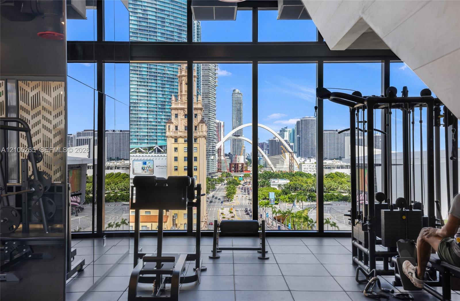Fitness center featuring floor-to-ceiling windows, panoramic urban skyline scenery, and large-format tile flooring