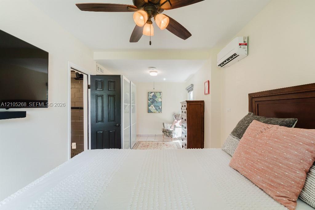 Ceiling fan with integrated lighting, wall-mounted air conditioning unit, and wood-finish headboard