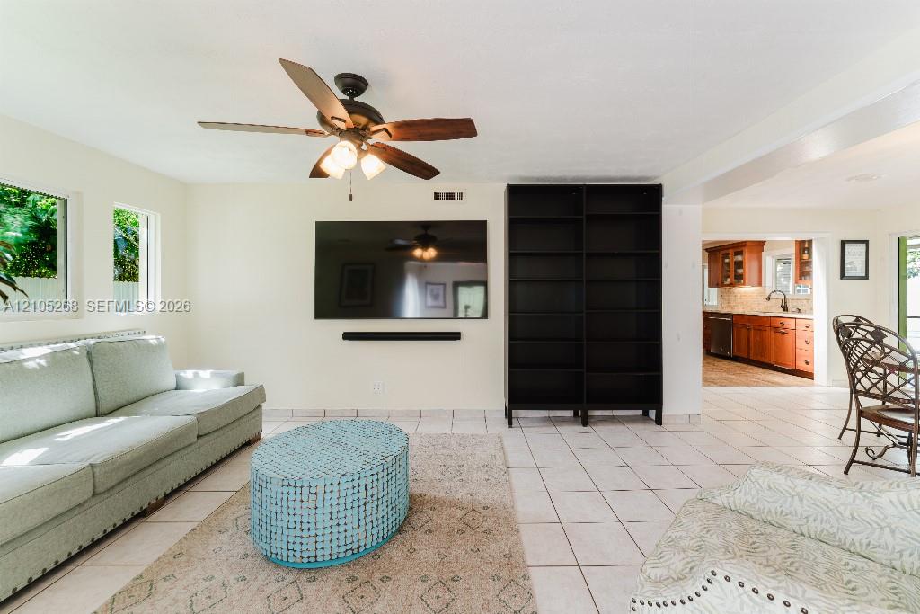 Recessed lighting, ceiling fan with integrated light fixture, mounted television, built-in shelving, and tile flooring