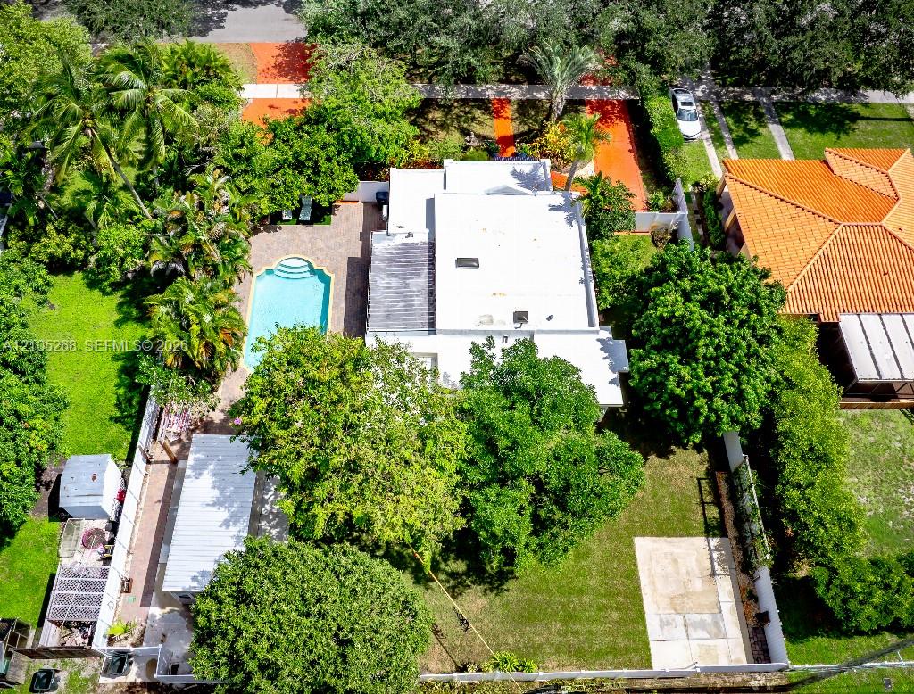 Rectangular residence with a flat roof, surrounded by mature trees and lush landscaping