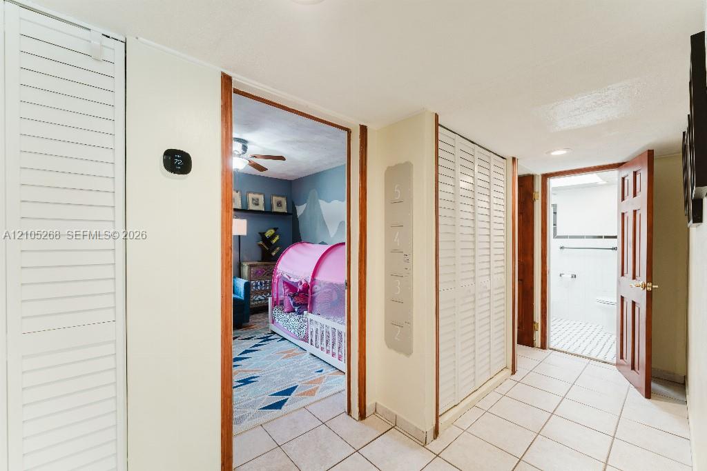 Hallway featuring tile flooring, louvered closet doors, and wood-finish door frames