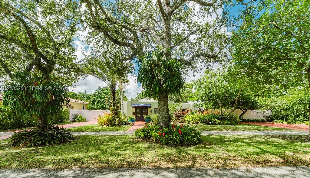 Expansive front yard featuring mature trees, manicured lawn, and lush landscaping