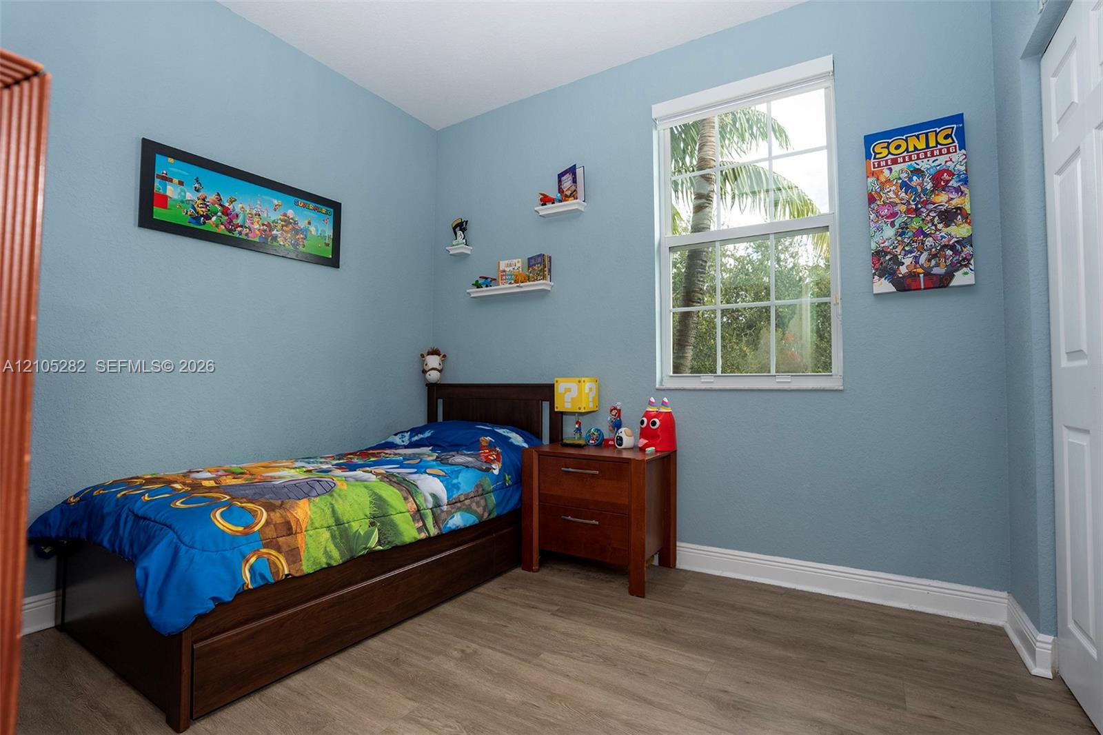 Wood-finish flooring, multi-pane window with white casing, and wall-mounted shelving