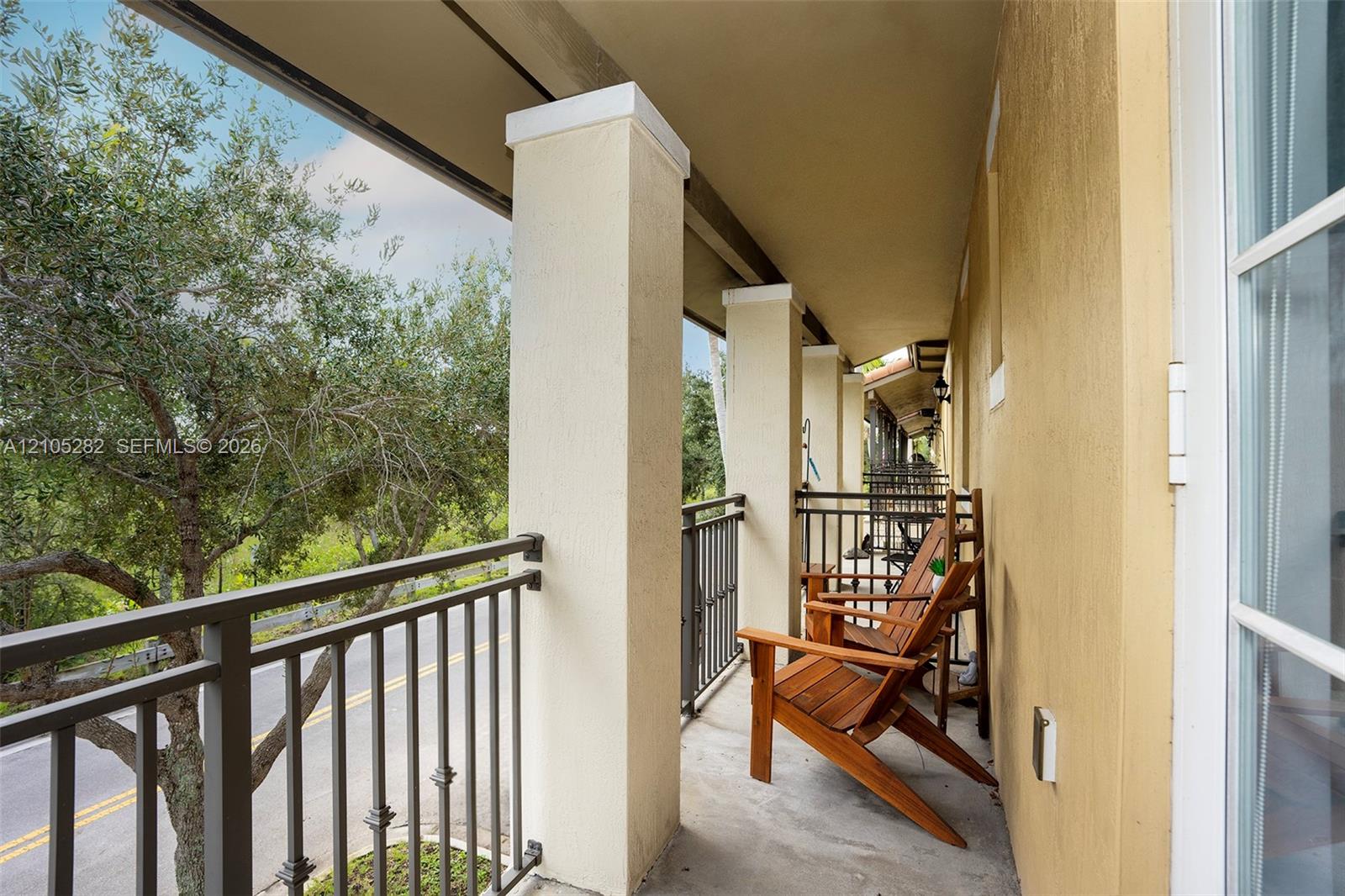 Covered balcony featuring concrete flooring, structural square columns, and a metal railing