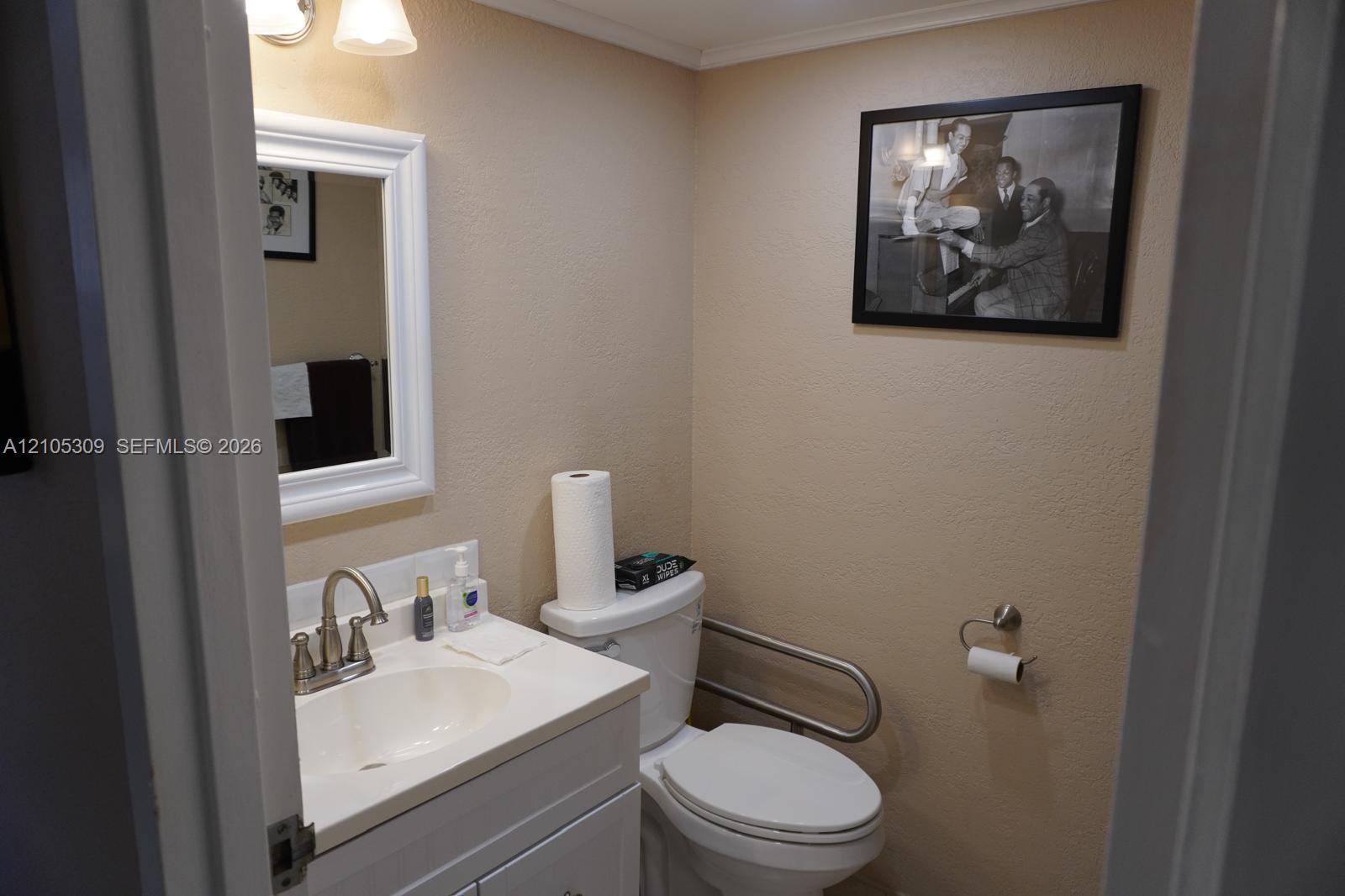 White vanity cabinet with an integrated basin, brushed nickel faucet, wall-mounted mirror, two-light fixture, and wall-mounted metal grab bar White vanity cabinet with an integrated basin, brushed nickel faucet, wall-mounted mirror, two-light fixture, and wall-mounted metal grab bar