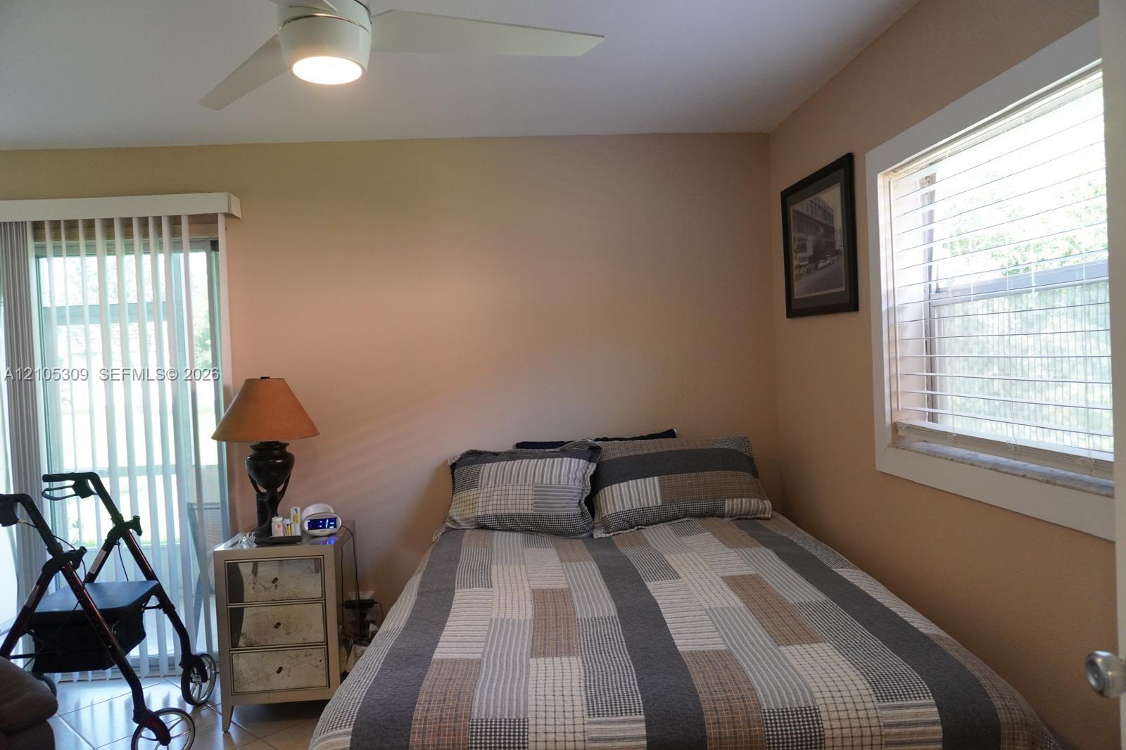 Room featuring neutral wall paint, a ceiling-mounted light fixture with fan, and a sliding glass door with vertical blinds Room featuring neutral wall paint, a ceiling-mounted light fixture with fan, and a sliding glass door with vertical blinds